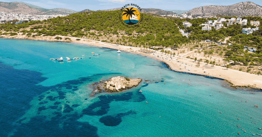 A scenic shot of Vouliagmeni Beach with sunbeds, umbrellas, and the tranquil Aegean Sea in the background.